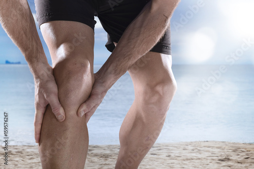 young sport man with athletic legs holding knee in pain suffering muscle injury running