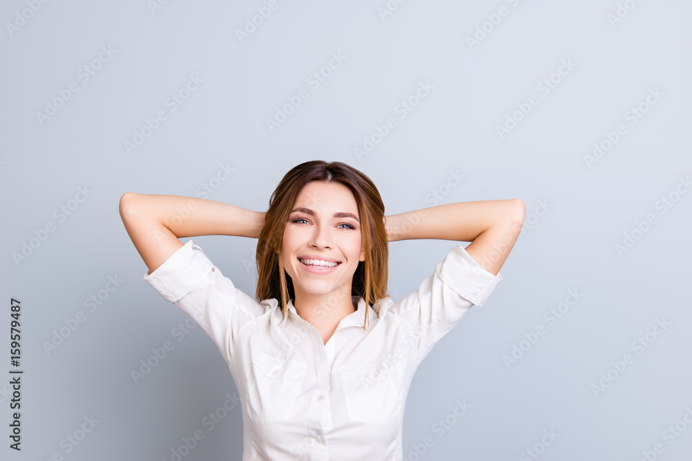 Time to rest. Young freelancer with beaming smile is relaxing, hands behind the head, dreaming and enjoying, in white shirt on pure background Time to rest. Young freelancer with beaming smile is relaxing, hands behind the head, dreaming and enjoying, in white shirt on pure background