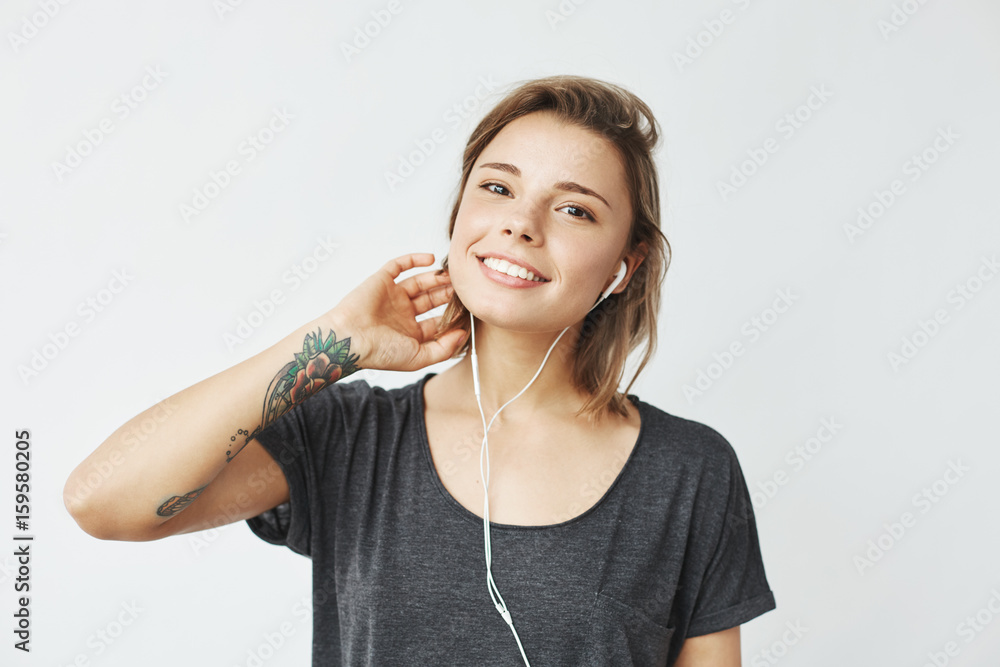 Portrait of young beautiful happy girl smiling looking at camera listening music in headphones over white background. Portrait of young beautiful happy girl smiling looking at camera listening music in headphones over white background.