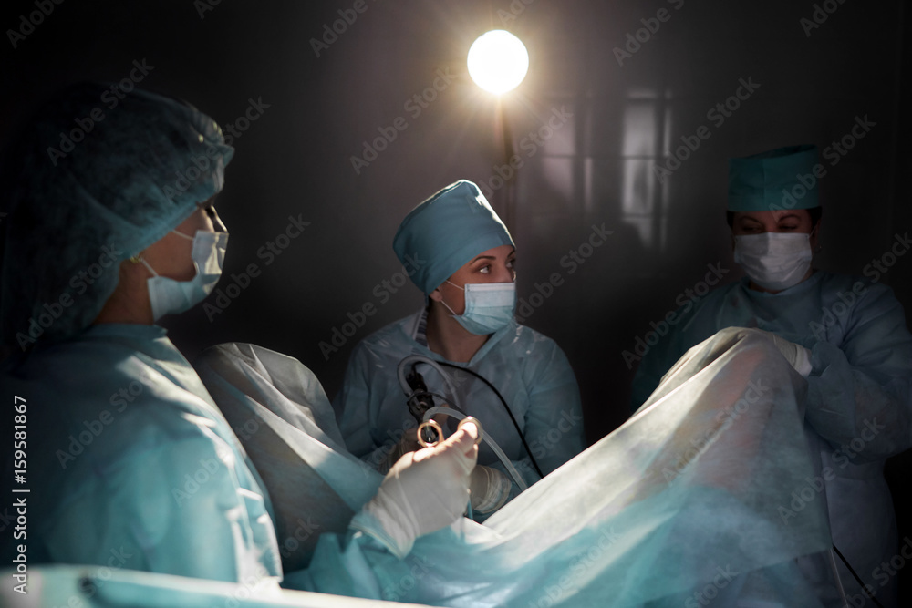 Group of surgeons working on a patient in operating room performing surgery living vitality profession occupation job practitioner teamwork people concept.