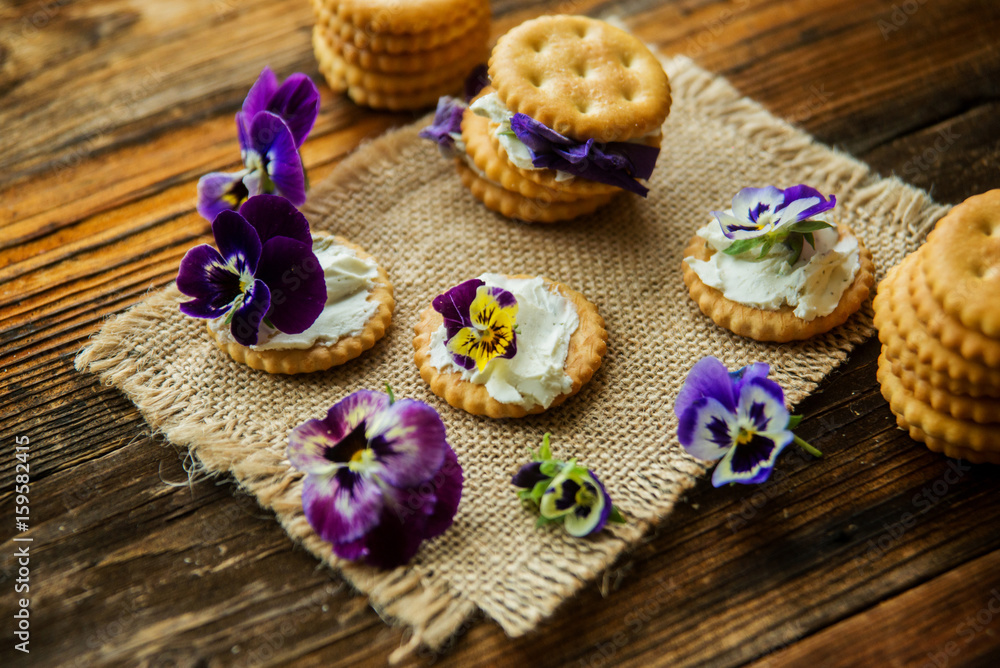 Sandwich with herb and edible flowers butter on wooden background, healthy food.