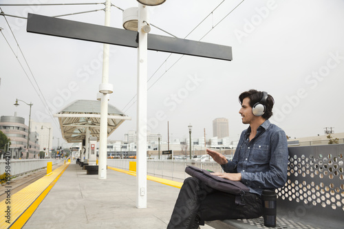 Man wearing headphones and drumming hands at station, Los Angeles, California, USA