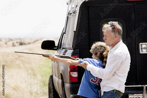 Father teaching son with rifle, Texas, USA photo