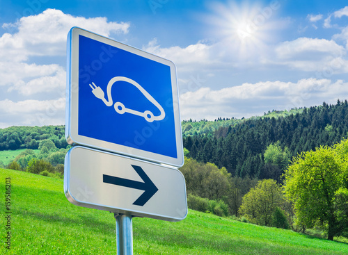 Wegweiser zur Solartankstelle für Autos vor traumhafter Landschaft mit strahlender Sonne - Trafic sign to the solar station for cars in front of a wonderfull landscape with a bright sun photo