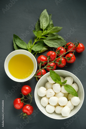Mozzarella cheese, basil and tomatoes cherry on a gray background.