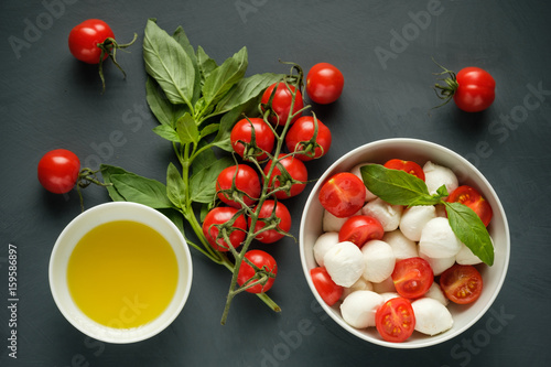 Mozzarella cheese, basil and tomatoes cherry on a gray background