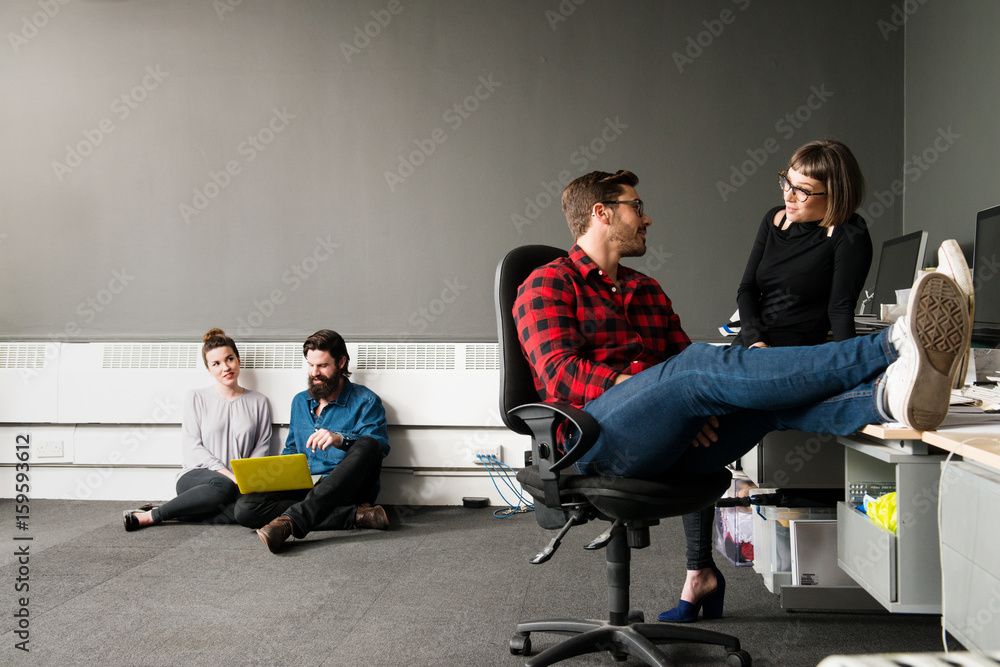 Young man sitting on office chair with feet up on desk Young man sitting on office chair with feet up on desk