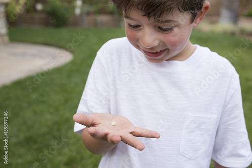 Young boy holding tooth in hand