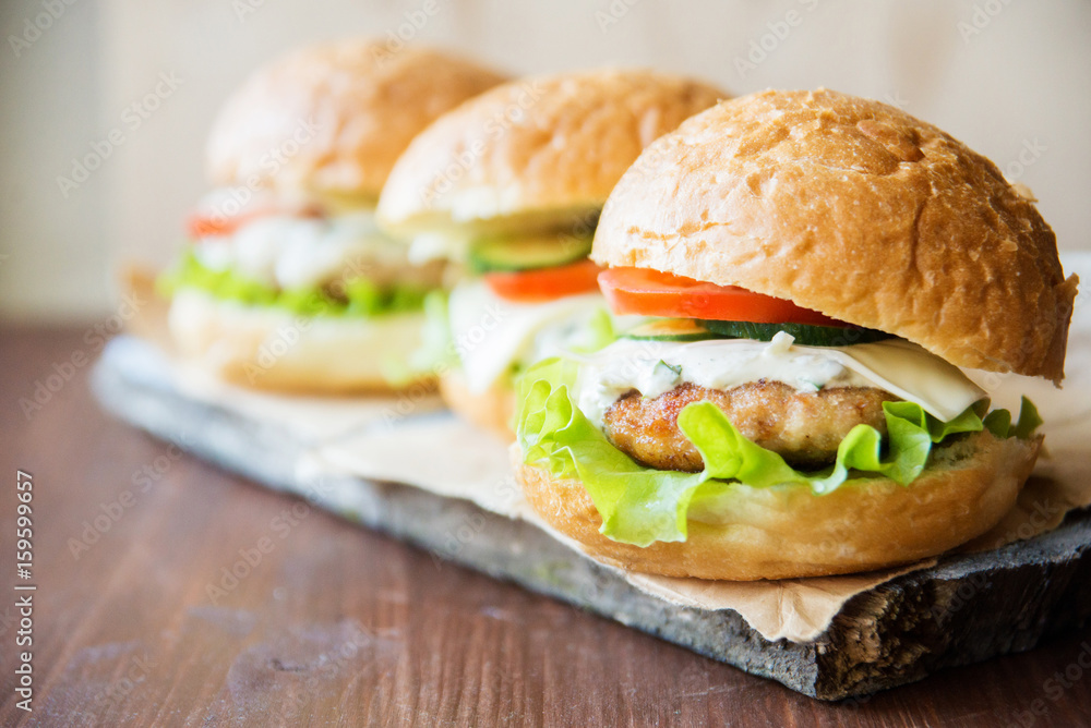 Closeup of home made burgers on wooden background Closeup of home made burgers on wooden background