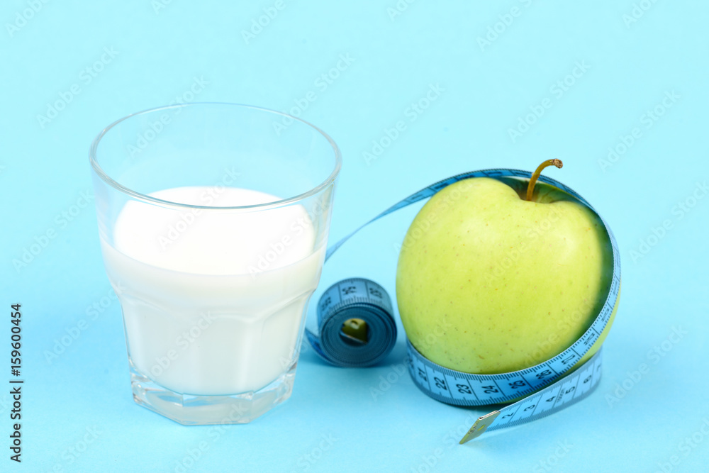 Glass of milk and apple wrapped around with measuring tape Glass of milk and apple wrapped around with measuring tape