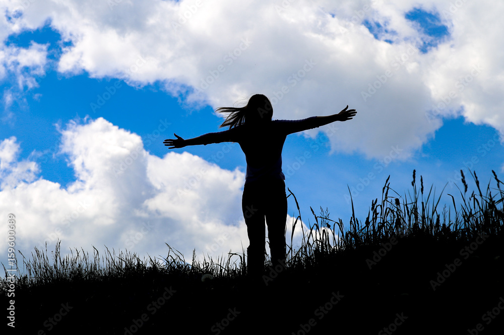 Silhouette young woman open arms on hill