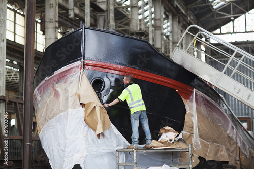 Workers unwrapping boat in shipyard