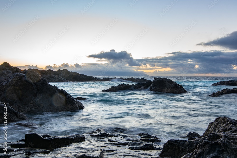 Rocky shore over the ocean during sunset.