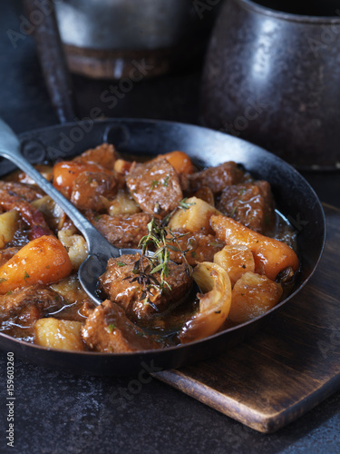 Daube of beef with onion, carrots, rosemary and  potatoes in vintage pan photo