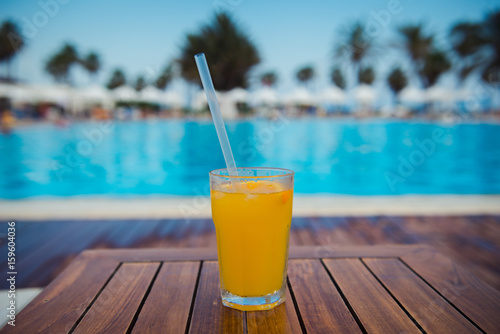 tropical cocktail on wooden table background pool