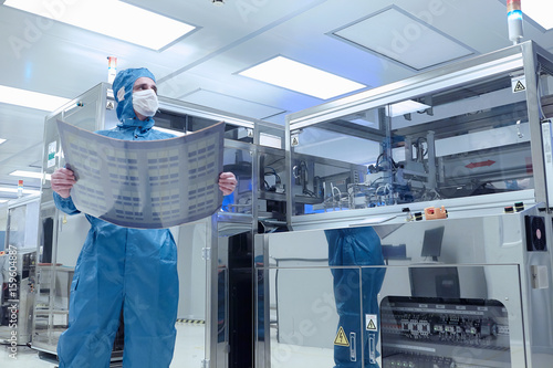 Male worker holding flex circuit in flexible electronics factory clean room photo