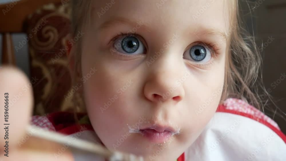Little Beautiful Blonde Girl with Blond Hair and Blue Eyes Eats Spoon Yogurt or Cottage Cheese Curd Little Beautiful Blonde Girl with Blond Hair and Blue Eyes Eats Spoon Yogurt or Cottage Cheese Curd
