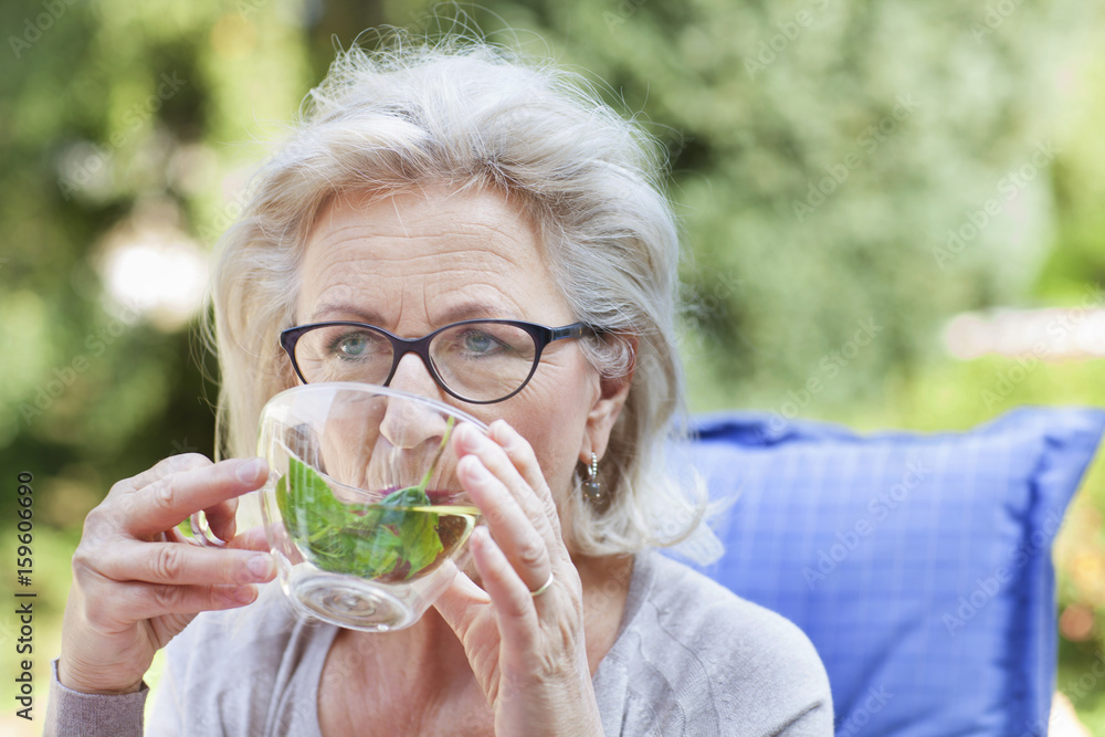 Senior woman, relaxing in garden, drinking drink Senior woman, relaxing in garden, drinking drink