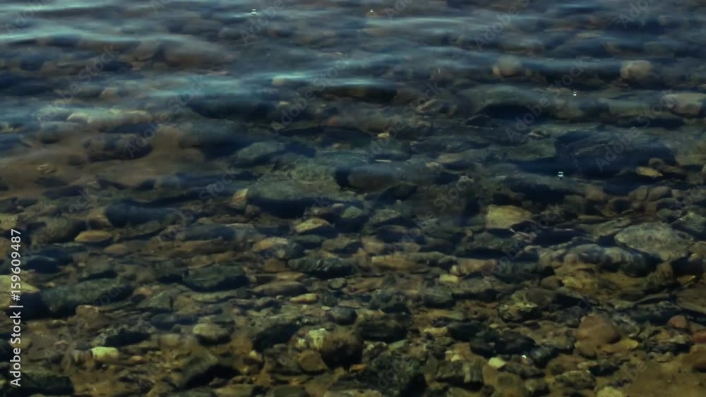Small waves roll on a stony bottom and clear water Small waves roll on a stony bottom and clear water
