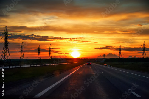 Highway with cars traveling on the sunset .