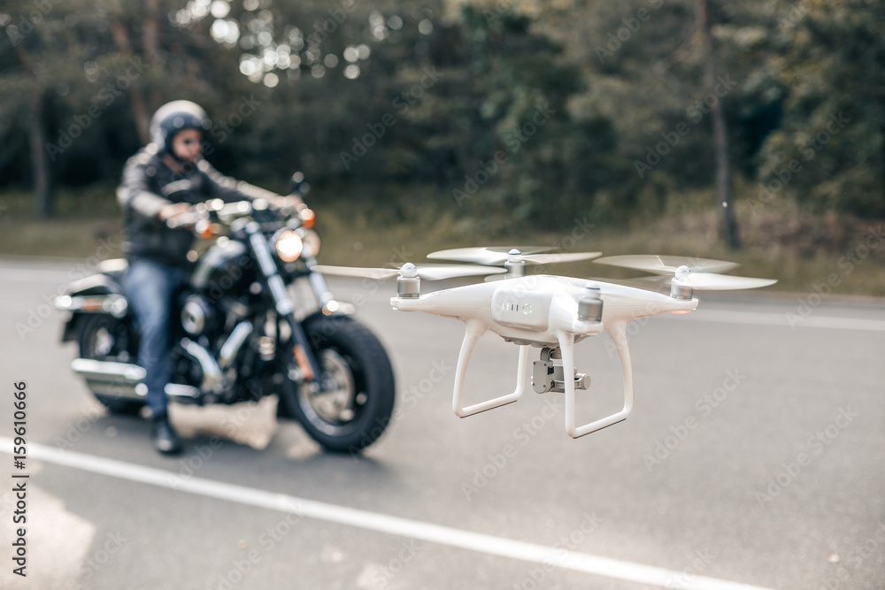 Motorbike on the road riding and hovering drone. Hovering drone taking pictures of biker. Motorbike on the road riding and hovering drone. Hovering drone taking pictures of biker.