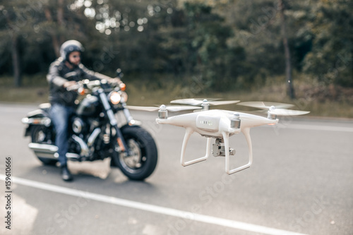 Motorbike on the road riding and hovering drone. Hovering drone taking pictures of biker.