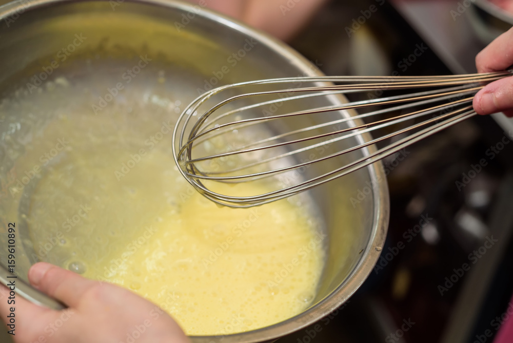 Fototapeta premium Close up female hand mixes ingredients with whisk