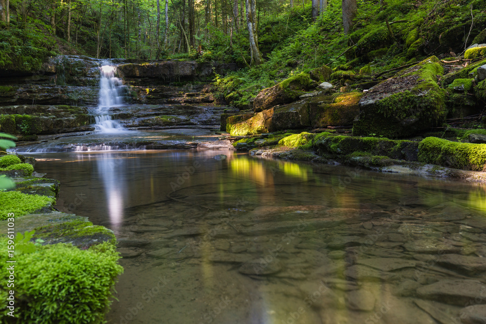 Obraz premium Romantischer Wasserfall im grünen Wald im Tennengau in Salzburg