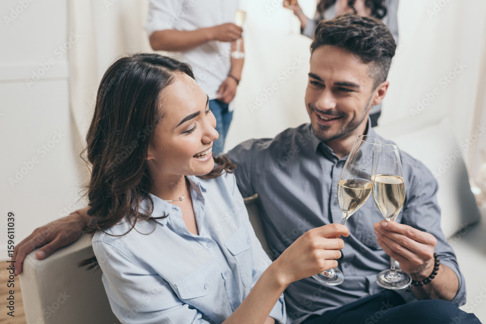 Obraz premium young couple clinking with champagne glasses at home party