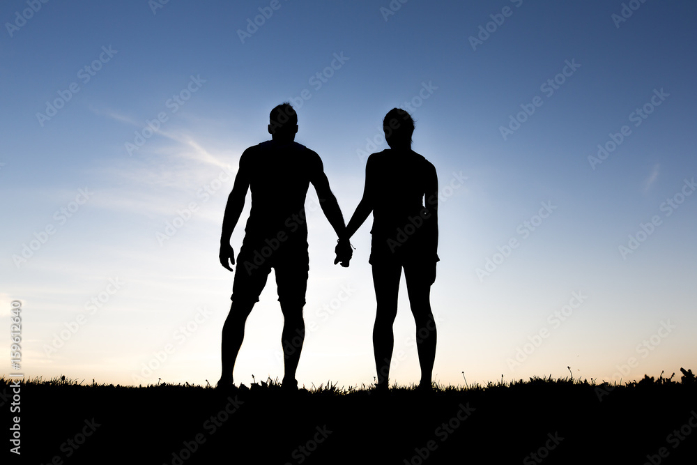 silhouette of romantic lovers with sunset on the back