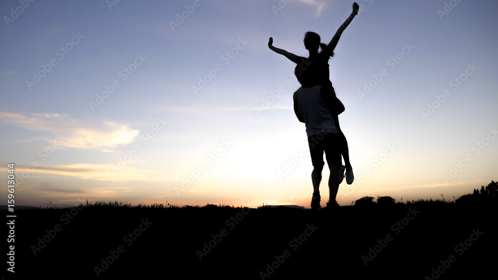 silhouette of romantic lovers with sunset on the back