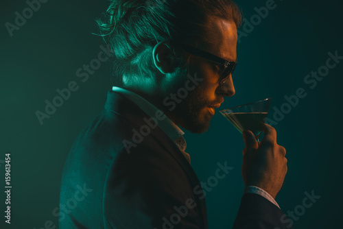 Canvas Print profile of young caucasian man in suit drinking cocktail from glass