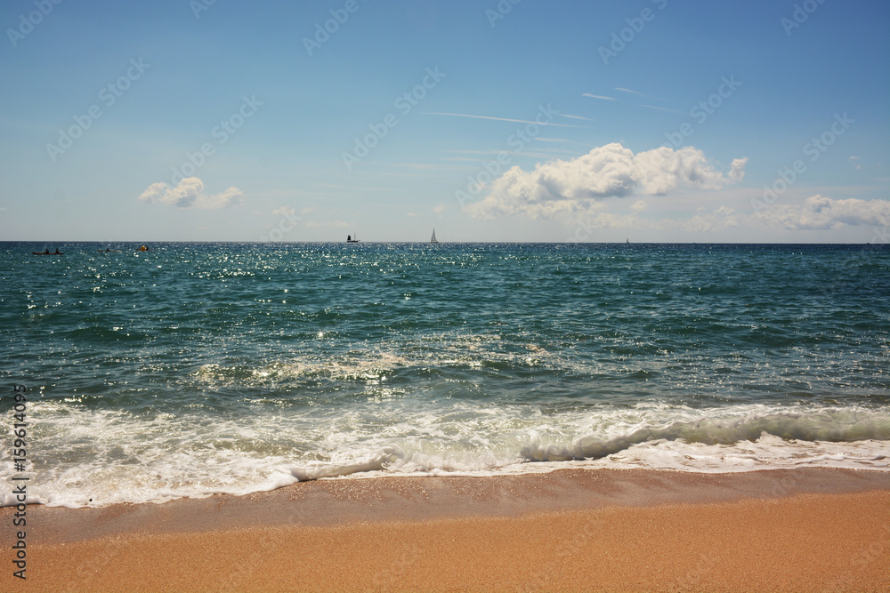 Clean sandy beach, azure Mediterranean sea, sailboat on the horizon