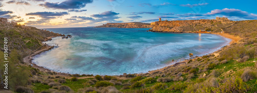 Mgarr, Malta - Panoramic skyline view of the famous Ghajn Tuffieha bay at blue hour on a long exposure shot with beautiful sky and clouds photo