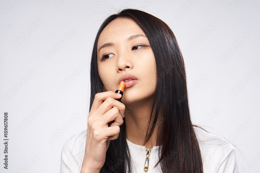 Woman is painting lipstick on a gray background Woman is painting lipstick on a gray background