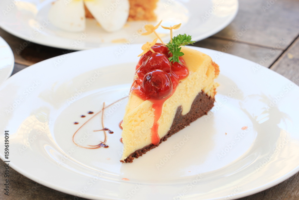 Slice of cheesecake with cherry sauce and ixora flower on white plate Slice of cheesecake with cherry sauce and ixora flower on white plate