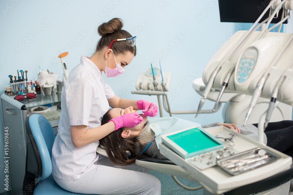 Female dentist with dental tools - mirror and probe treating patient teeth at dental clinic office. Medicine, dentistry and health care concept. Dental equipment Female dentist with dental tools - mirror and probe treating patient teeth at dental clinic office. Medicine, dentistry and health care concept. Dental equipment