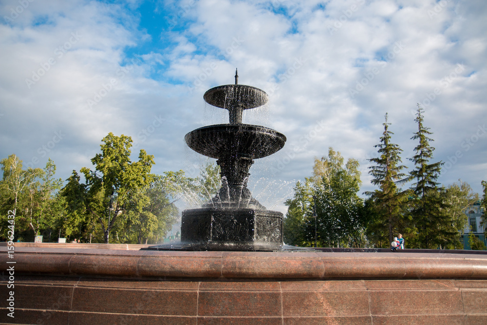 Large granite fountain in a city park on a background of a bright blue sky Large granite fountain in a city park on a background of a bright blue sky