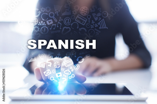 Woman is using tablet pc, pressing on virtual screen and selecting spanish.