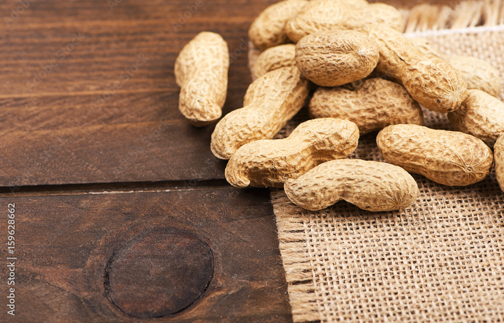 Fototapeta premium From above peanuts on canvas bag. Wooden background. Copy space.