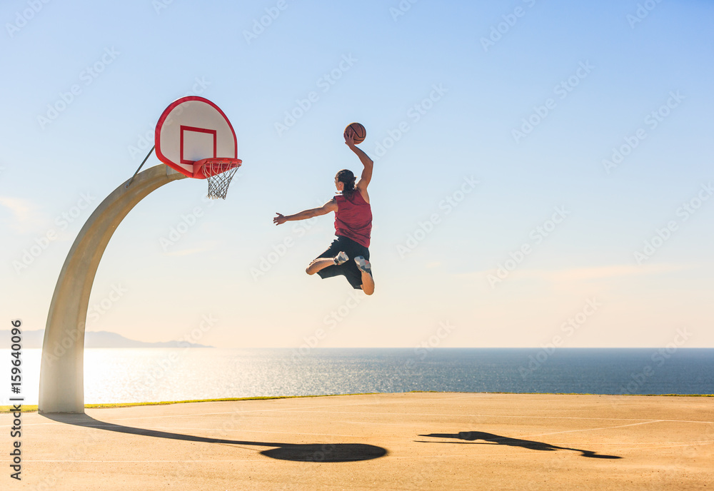 Obraz premium Basketball Player scoring an amazing slam dunk outdoors.