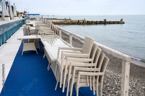 Row of wicker chairs stacked on each other and cafe tables along the embankment. Start/end of tourist season