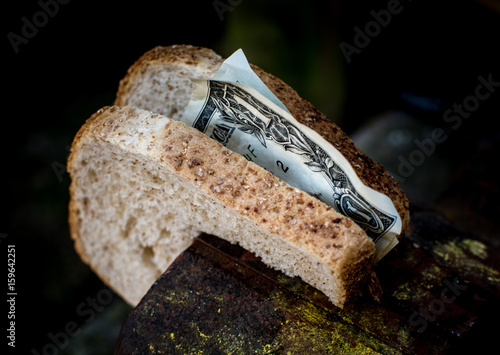 Foto Two pieces of bread with the money Clamped in a metal vise.