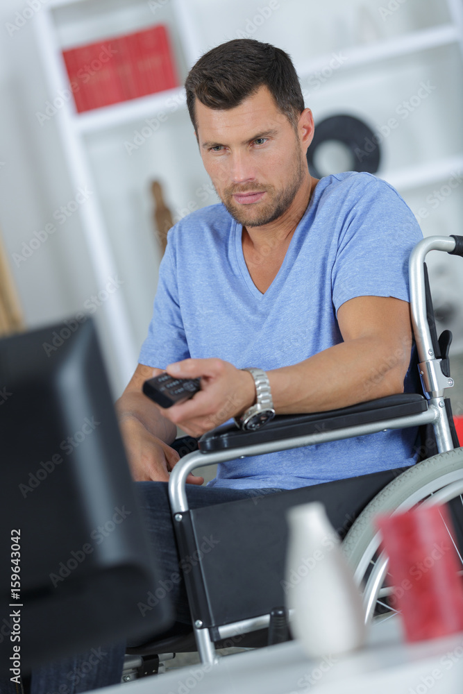handsome handicapped man watching television in living room