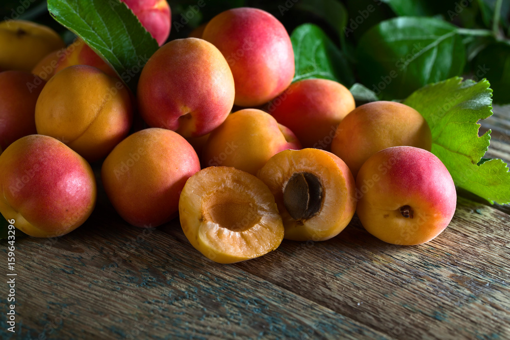 Juicy fresh apricots with leaves on old wooden table . Juicy fresh apricots with leaves on old wooden table .