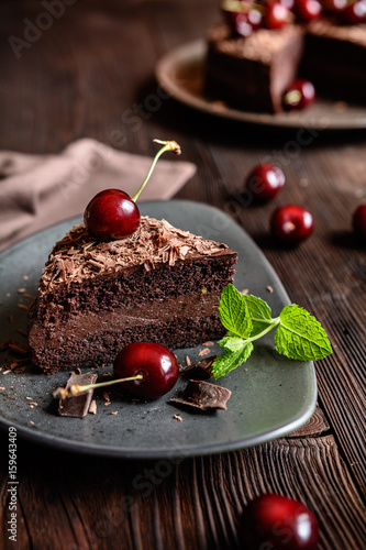 Chocolate cake filled with cocoa whipped cream and decorated with chocolate shavings and cherry