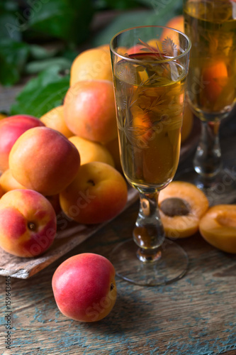 Juicy apricots with leaves and glass of sweet wine .