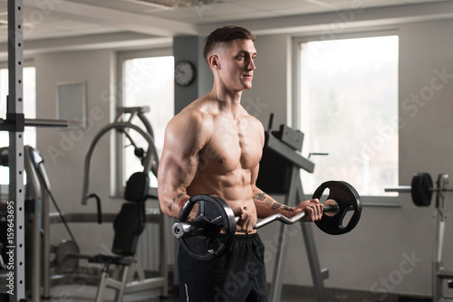 Muscular Young Man Exercising Biceps With Barbell