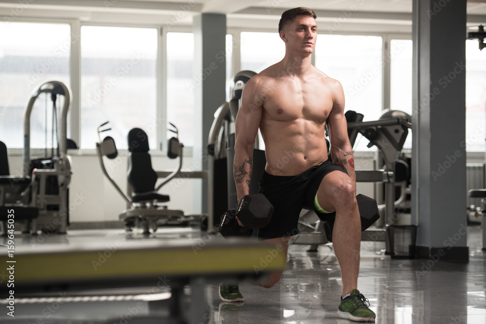 Fitness Man Using Dumbbells Exercising Legs Inside Gym