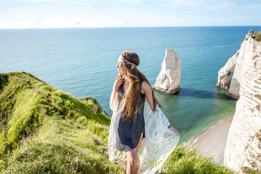 Young woman dressed in hippie style enjoying nature on the rocky coastline with great view on the ocean in France Young woman dressed in hippie style enjoying nature on the rocky coastline with great view on the ocean in France
